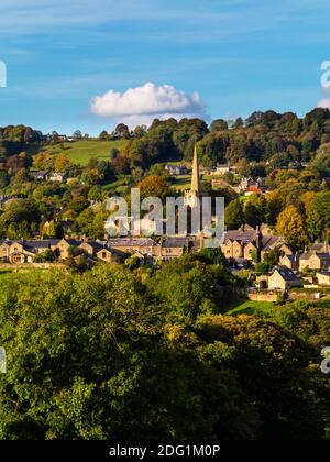 View of Ashover a village in North East Derbyshire England UK close to the Peak District with the church and houses visible and trees in foreground. Stock Photo