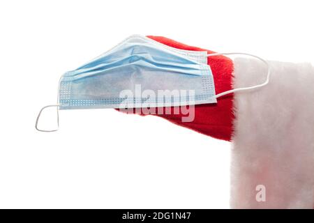 Close up side shot of Santa Claus's hand holding a medical mask. New normal, new reality concept. Safe winter holidays concept. Isolated on white back Stock Photo