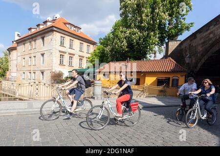 People Tourists in Prague on a rental bike under Charles Bridge Prague Czech Republic Europe Stock Photo