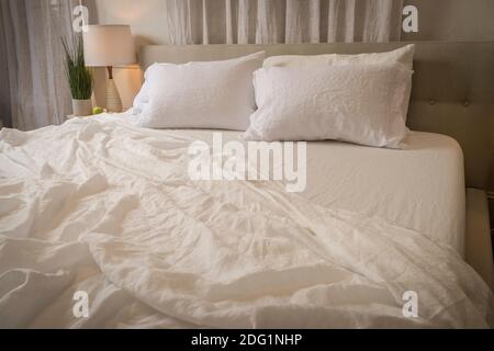 Wrinkled bed sheets in messy bedroom, USA Stock Photo