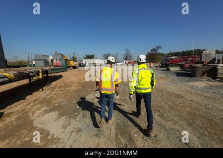 Two construction workers walking away from construction site, Baltimore Maryland USA Stock Photo