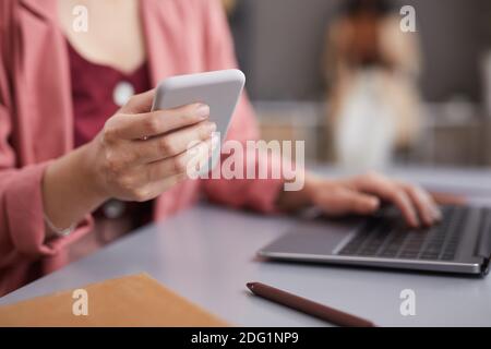 Close up of modern successful businesswoman holding smartphone at desk in home office, copy space Stock Photo