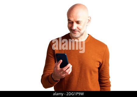 Portrait shot of smiling senior man text messaging while standing at isolated white background. Stock Photo