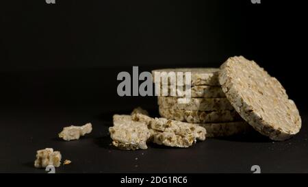 Grain crispbreads crispy rice and diet bread. Stack of puffed whole grain crispbread. Rice cake puffed rice on black background Stock Photo