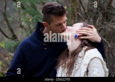 Young couple kissing in the forest in front of trees Stock Photo