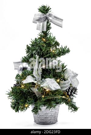 A beautiful mini Christmas tree with silver decorations and warm lighting. Isolated on white background. Stock Photo