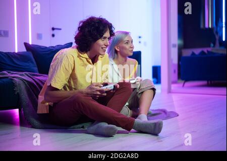 Photo of young couple playing video games at home at night Stock Photo