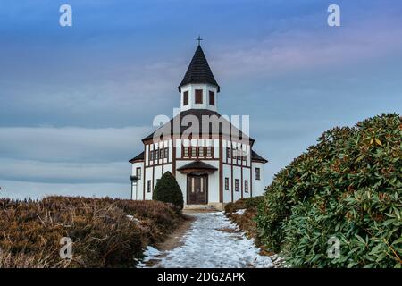 Small white rural Tesarovska chapel with cemetery in the village of Korenov, Jizera mountains, Czech Republic. View of winter landscape at sunset.Wood Stock Photo