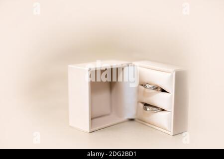 Close up of wedding rings in a light beige box over a light beige surface - selective focus, copy space. Stock Photo