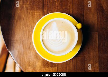 Yellow cup of aromatic coffee on a wooden table. Stock Photo