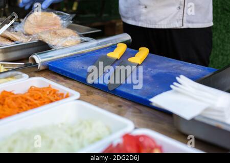open air kitchen products for cooking falafel in dishes on a wooden table. Street food ready to serve on a food stall. Stock Photo