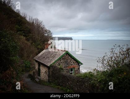 View looking down to the coastline from Bucks Mills village in Devon, England with artist's cabin and Lundy Island visible on horizon. November 2020 Stock Photo