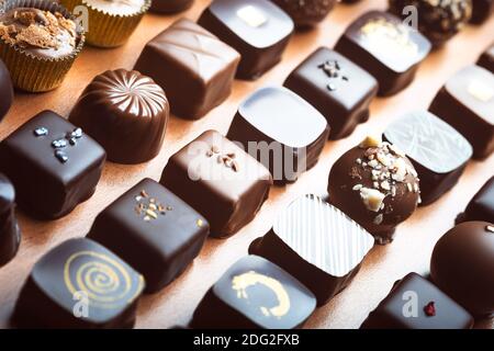 Mixed luxury dark and milk chocolate truffles. Assorted delicious handmade chocolate pralines in a row. Full frame background. Studio shot. Close-up. Stock Photo