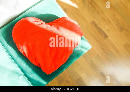 Heart shaped small decorative pillow on soft green pouffe. Modern interior cozy design element Stock Photo