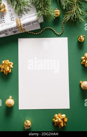 Empty vertical blank for Christmas Carols and sings decorated golden balls on green background. View from above. Stock Photo