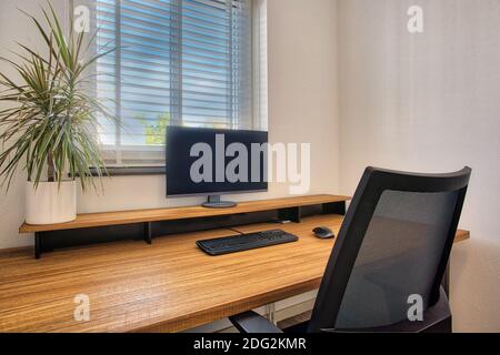 Workplace with laptop on wooden table at home by the window, home office, the new normal comfortable moden interior Stock Photo