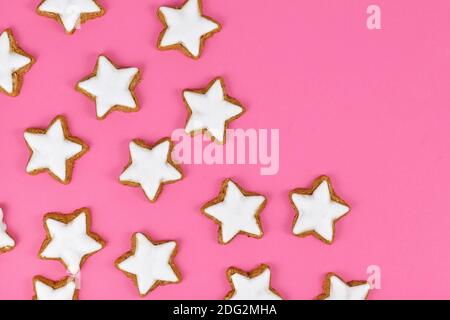 German star shaped glazed cinnamon Christmas cookies called 'Zimtsterne' on pink background Stock Photo