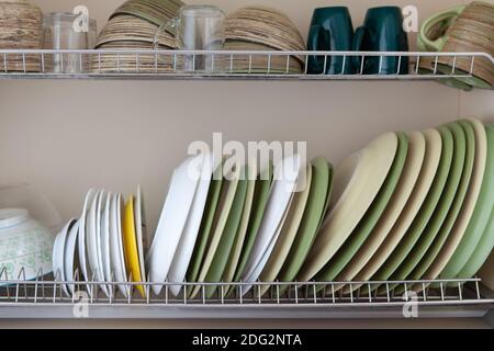 Clean dishes in white and green tones in a drying cabinet. Cups, glasses, mugs, plates, bowls, saucers on metal shelves. Concept for kitchen interior, Stock Photo