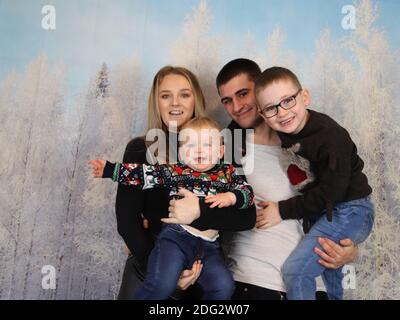 A traditional happy family Christmas photoshoot with a Christmas backdrop Stock Photo