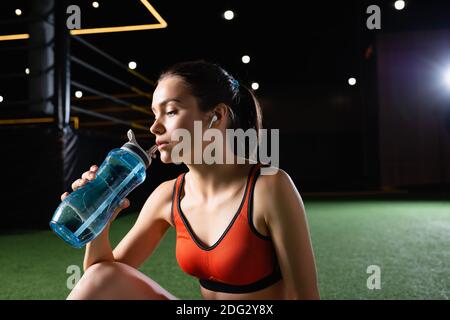young sportswoman drinking from sports bottle in gym Stock Photo