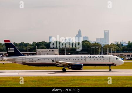 Commercial jet on an airport runway with city skyline in the background. Stock Photo