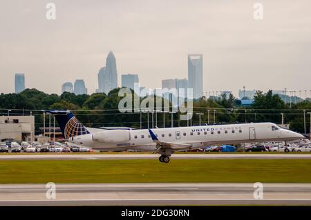 Commercial jet on an airport runway with city skyline in the background. Stock Photo