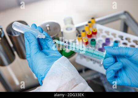 A medical worker types medicine into a syringe . Ampoule and syringe close-up. The concept of vaccination against coronavirus. Stock Photo