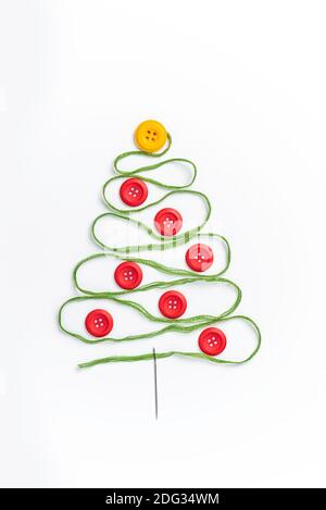 Sewing theme creative flat lay design: Christmas tree made of needle, thread and buttons on white background Stock Photo