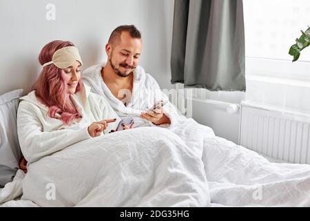 couple spend time on bed in the morning, adorable married man and woman in bathrobes at weekends, have rest. love concept Stock Photo