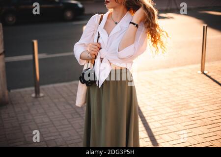 Woman with camera standing on street in city during summer Stock Photo