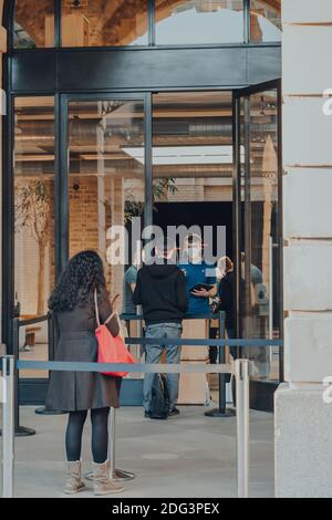 London, UK - November 19, 2020: People picking up orders outside Apple Store in Covent Garden, staff and customer wearing face shields PPE. Apple Cove Stock Photo