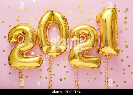 2021 air balloon gold numbers with ribbons golden confetti on pink background, Christmas, Happy New year eve decor with gold foil balloons 2021 Stock Photo