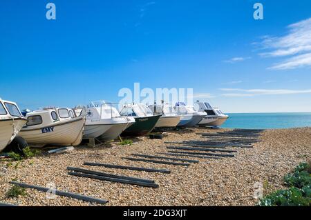 A line of boats on shingle beach on a sunny day, Eastbourne, East Sussex, England, UK Stock Photo