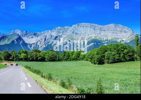 Panoramic view on Breche de Faraut mountain range in French Prealps and green fields in summer Stock Photo