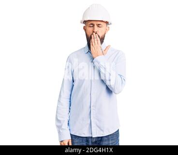 Young handsome man wearing architect hardhat bored yawning tired covering mouth with hand. restless and sleepiness. Stock Photo