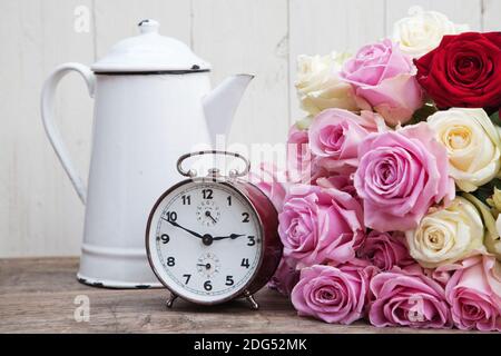 Still life picture of a rose bouquet an old alarm clock and an old coffee can Stock Photo