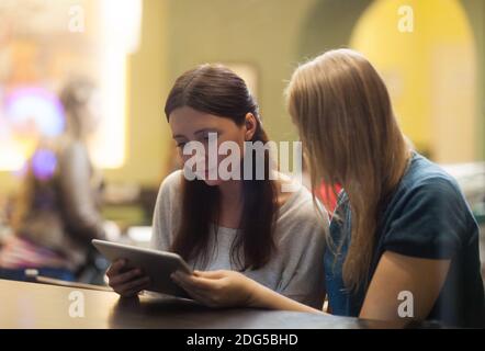 Two women in the restaurant using electronic tablet Stock Photo