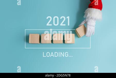 Loading new year 2020 to 2021 with hand of Santa Claus putting wood cube in progress bar. Stock Photo