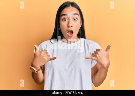 Young asian woman doing shaka sign with hands afraid and shocked with surprise and amazed expression, fear and excited face. Stock Photo