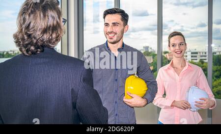 Two Caucasian architect or engineer holding helmet and smiling handshake for success project. Engineering business occupation. Stock Photo