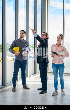 Group of Caucasian engineer teamwork standing meeting and pointing to something for planning project. Professional corporation people. Stock Photo