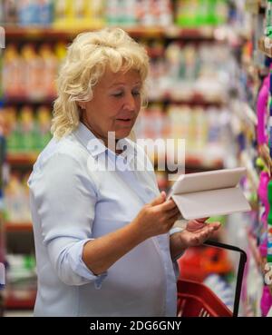 Woman using tablet PC in household chemicals section Stock Photo