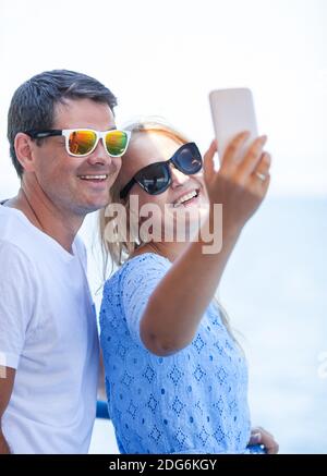 Cheerful couple in sunglasses taking mobile selfie Stock Photo