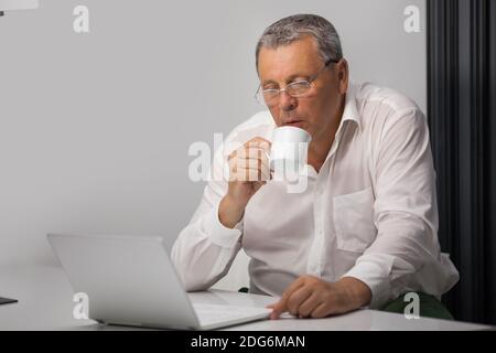 Businessman drinking coffee while working in office Stock Photo