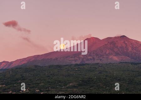 Eruption Volcano Etna at dawn with super moon at background in Sicily, Italy Stock Photo