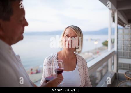 Senior woman drinking wine with husband on balcony Stock Photo