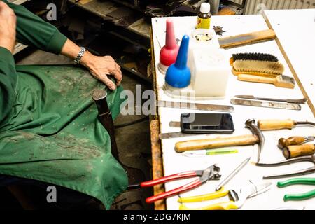 Preetz, Germany. 19th Nov, 2020. Tools and a smartphone are on a table in front of Reimer Bünn. Preetz' last cobbler closes his shop on 15 December 2020 and begins his retirement. (to dpa 'Cobbler town Preetz loses its last master shoemaker') Credit: Frank Molter/dpa/Alamy Live News Stock Photo