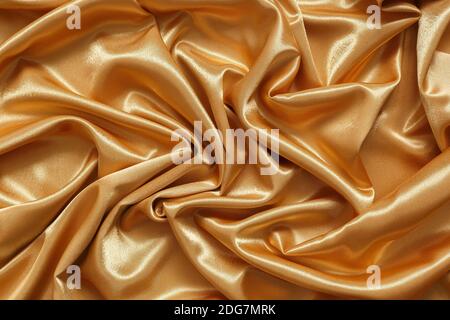 Abstract background of crumpled shiny, smooth golden fabric Stock Photo