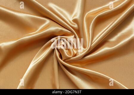 Abstract background of crumpled shiny, smooth golden fabric Stock Photo