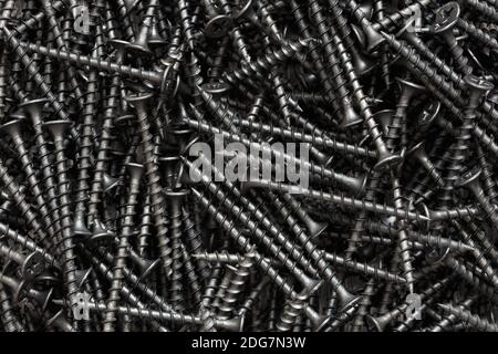 Steel black self-tapping screws close up, industrial background. Stock Photo